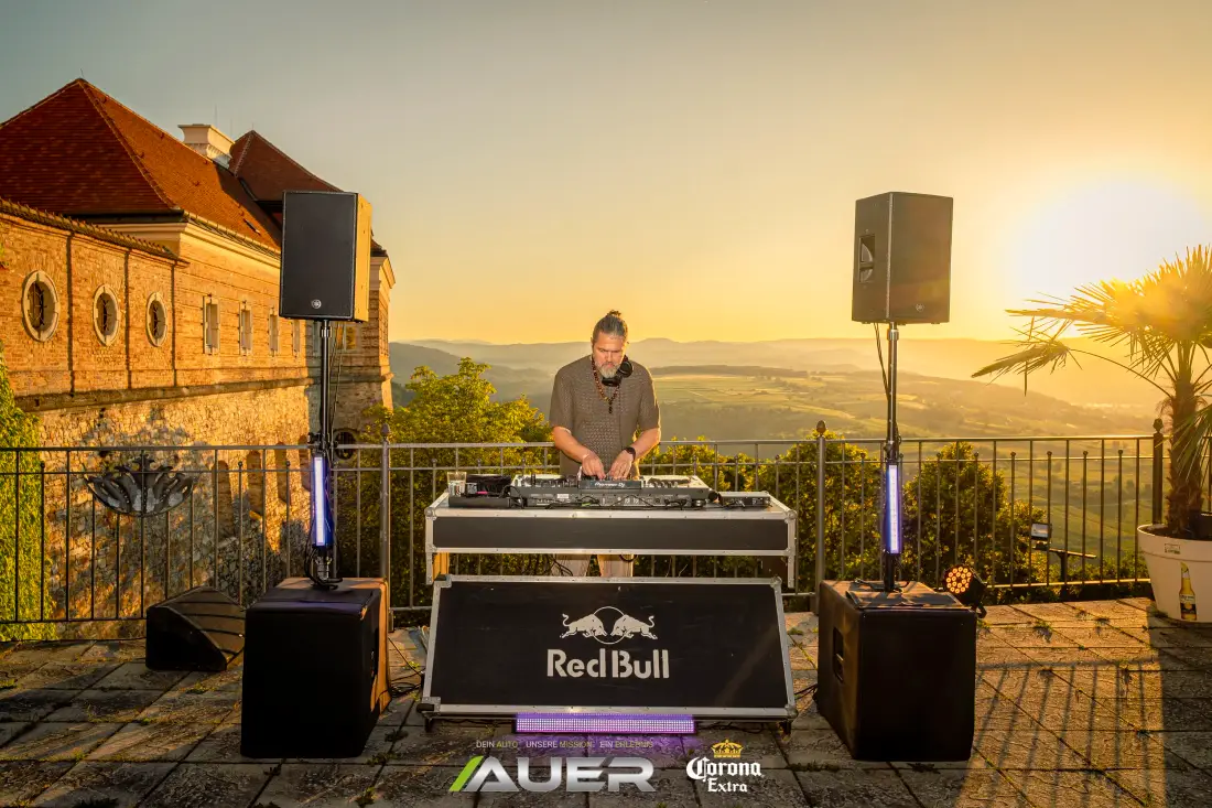 DJ playing at sunset on a terrace with a distant view