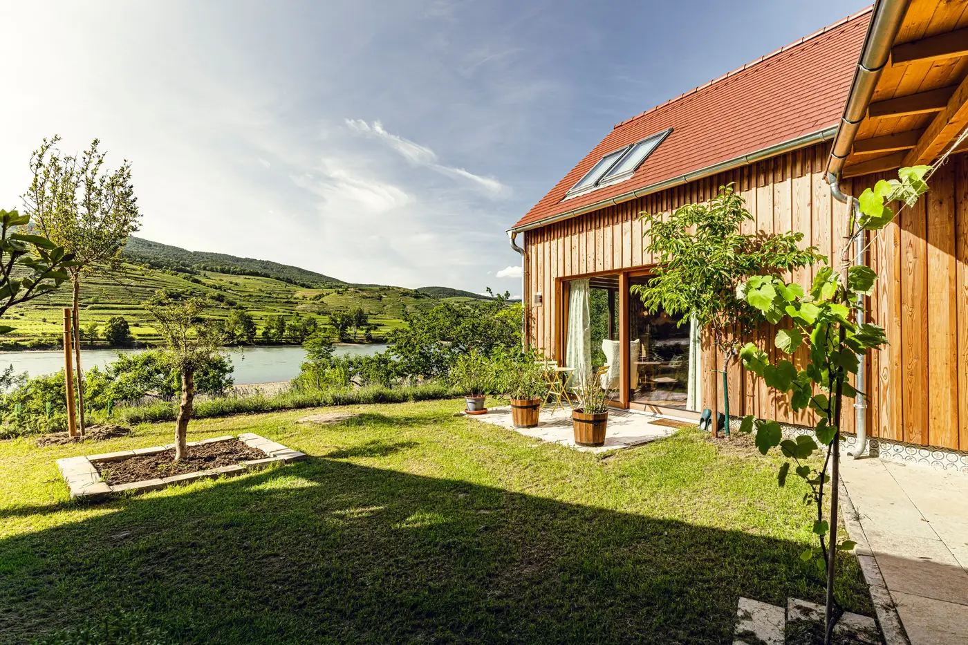 Holzhaus mit Garten, im Hintergrund die Donau und Weinterrassen