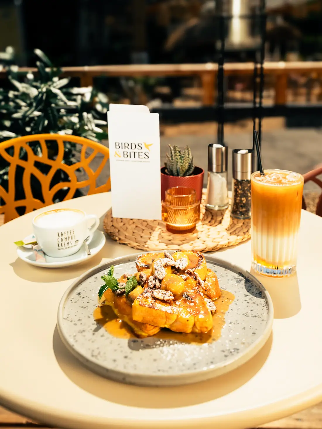 Frühstückstisch im Freien mit French Toast, Kaffee und einer Karte von Birds & Bites