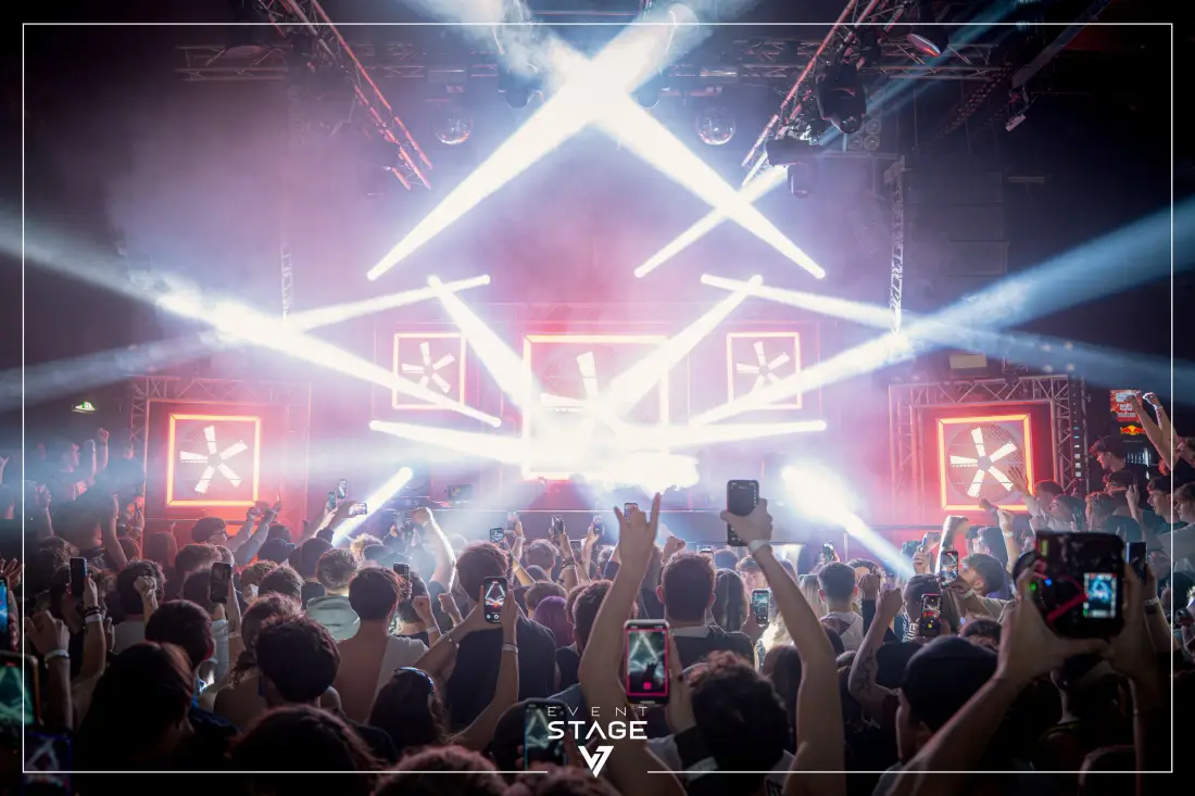 Stage show with white light beams, the audience with raised hands in front