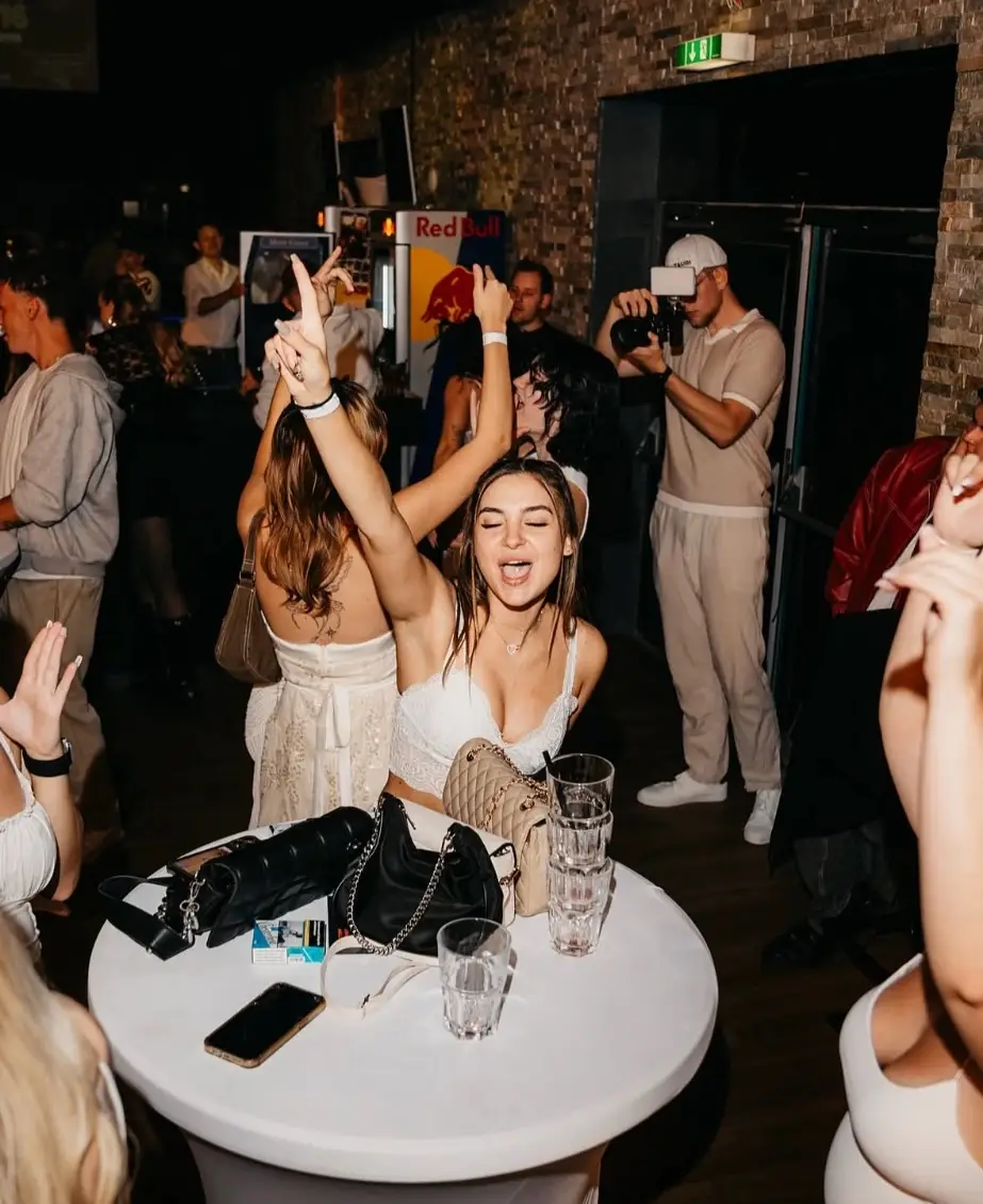 Photographer with camera among dancing guests at the All White Party