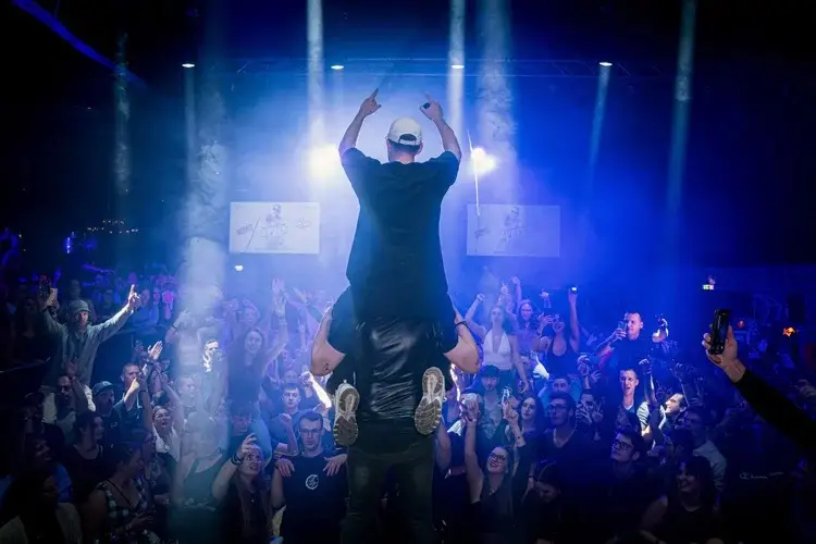 Artist on a man's shoulders celebrating with the crowd in the spotlights