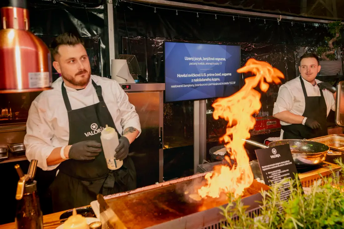 Two chefs flambéing at a show kitchen