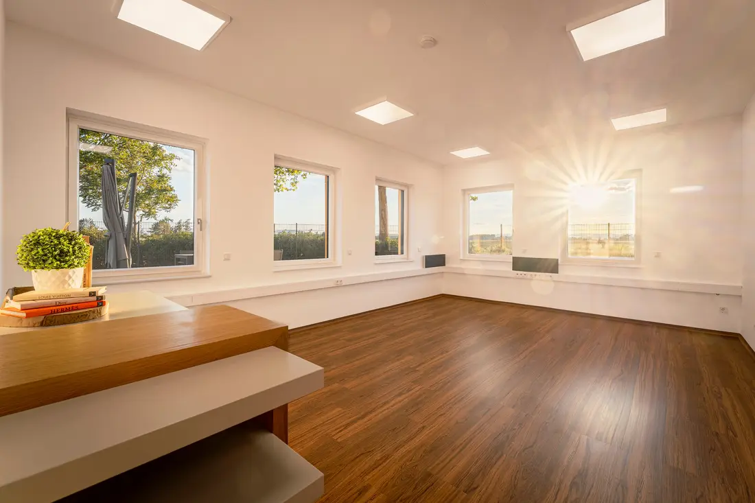 Leerer Büroraum im Wagram@Work mit dunklem Holzboden, durch die Fenster scheint die Abendsonne