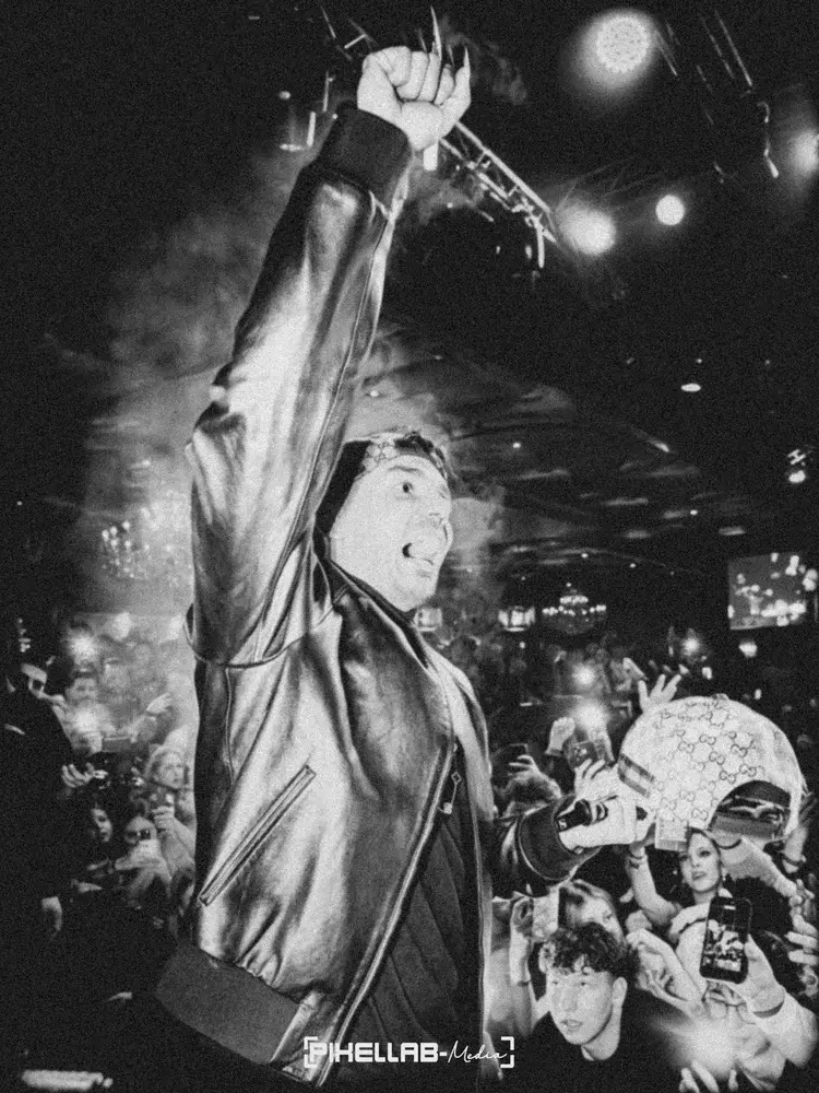 Rapper in a leather jacket raises his fist in front of the crowd, black-and-white photo