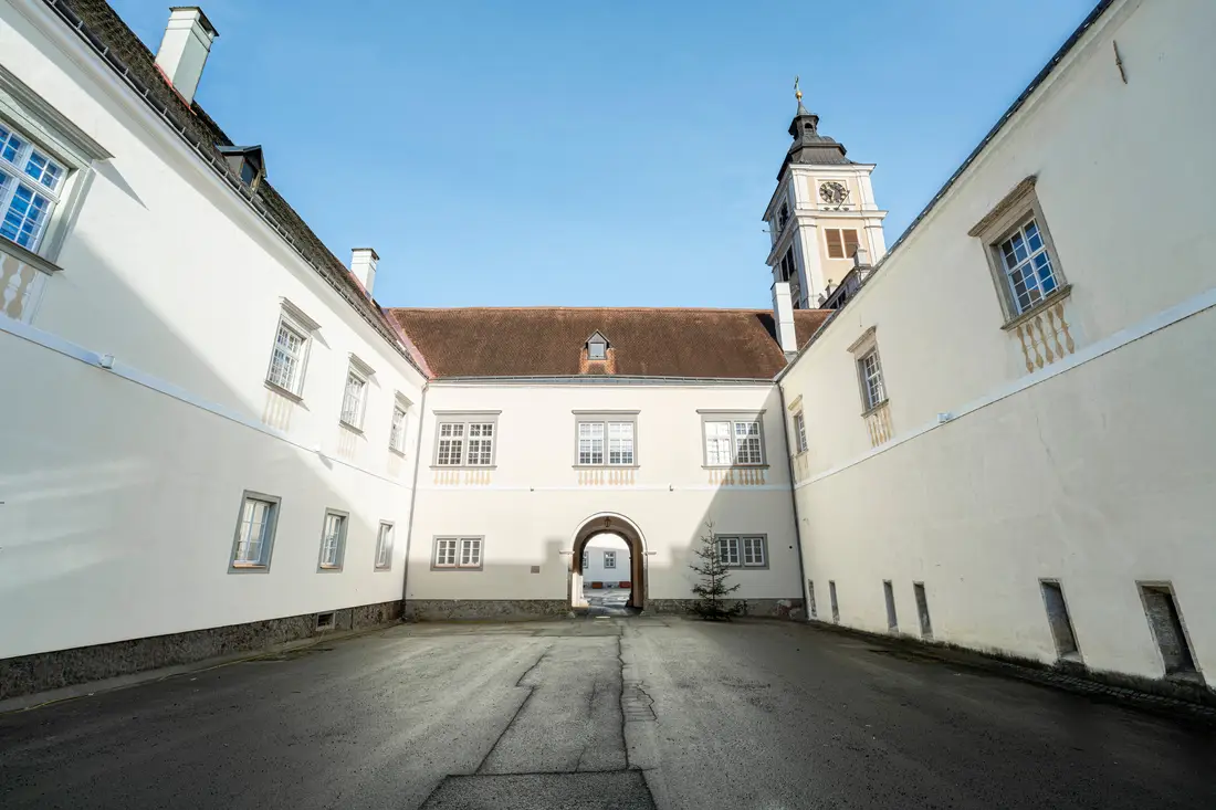 Innenhof eines weißen historischen Gebäudes mit Kirchturm