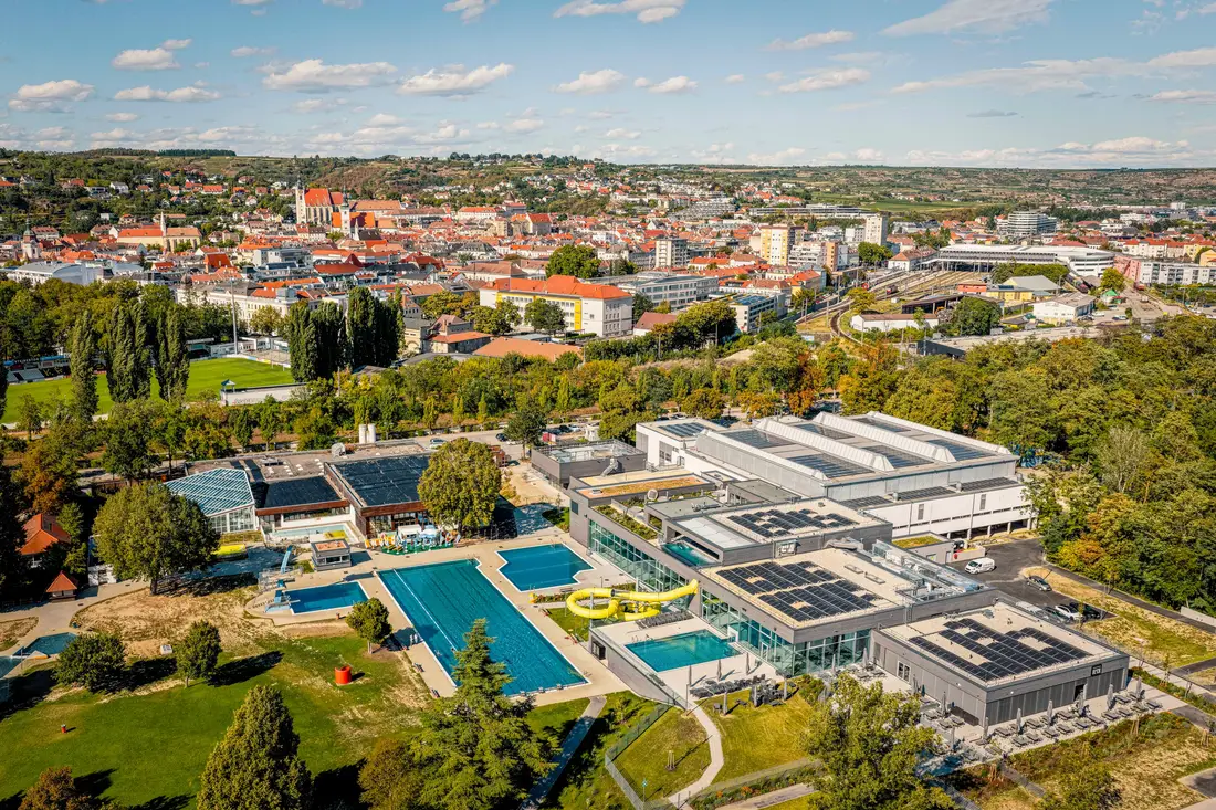 Luftaufnahme des Bads Mirador in Krems mit Freibecken und gelber Rutsche, dahinter die Stadt