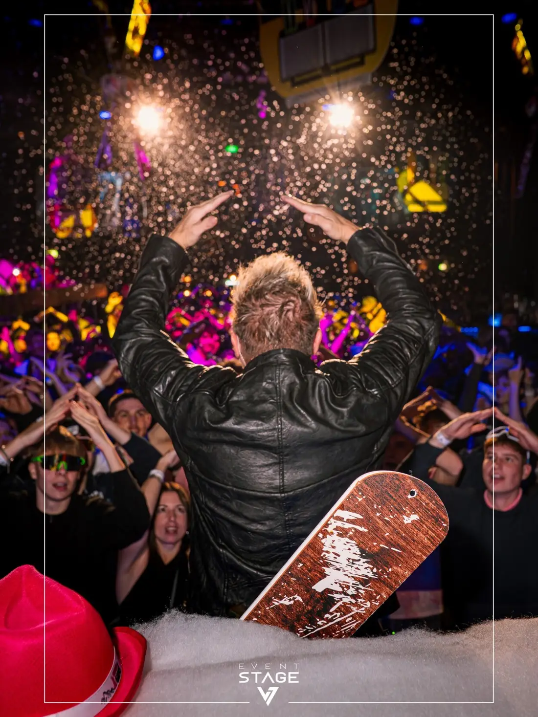 Artist from behind with raised arms, artificial snow flying over the crowd