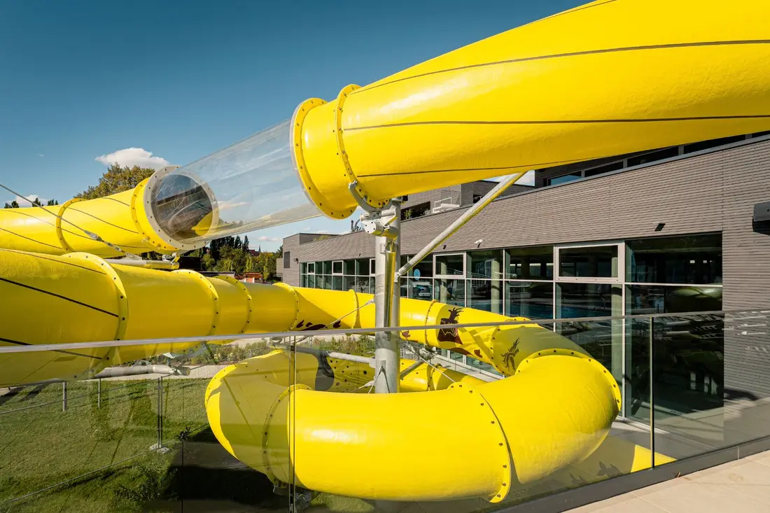 Yellow Aquarena tube slide with a transparent section, photographed from the roof terrace of Bad Mirador