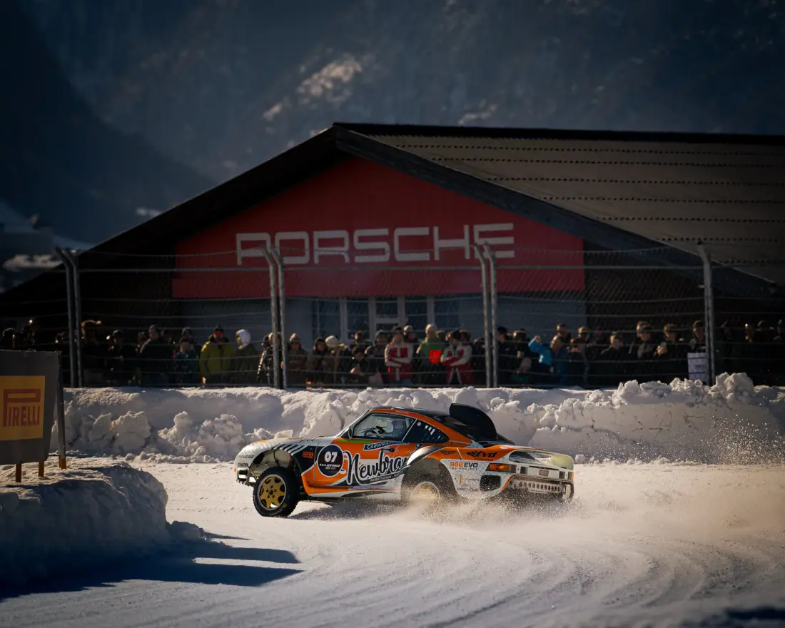 Rallyefahrzeug driftet im Schnee vor einem Porsche-Zelt