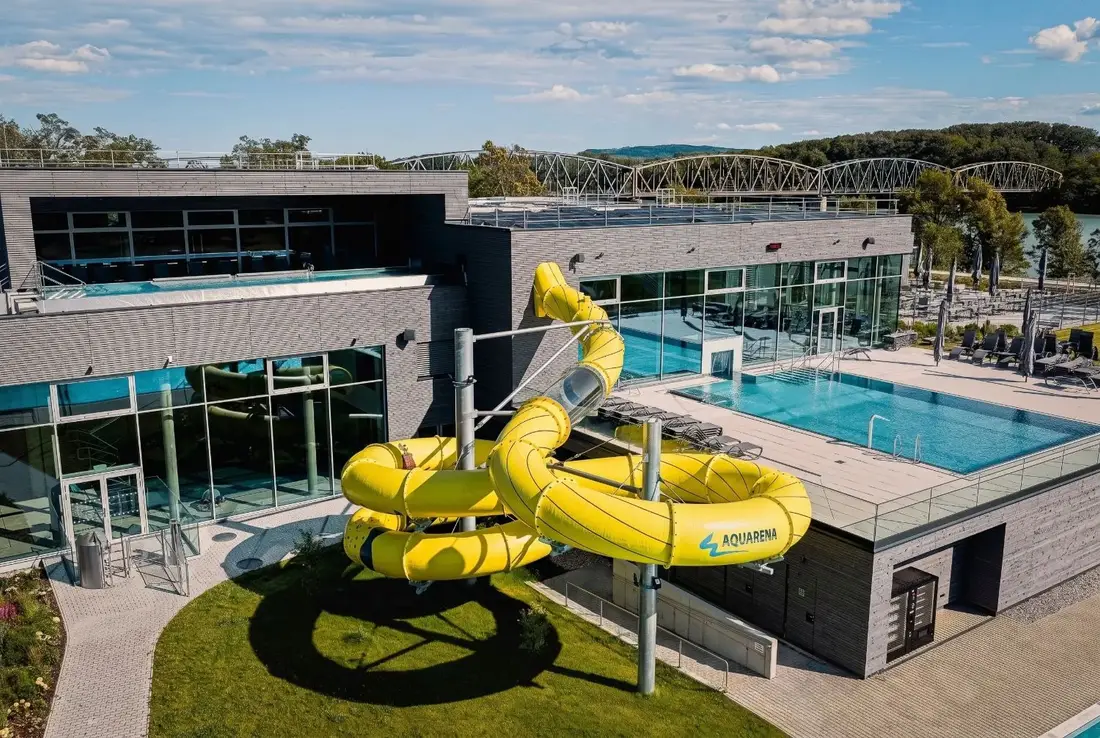 Aerial view of the Aquarena slide at Bad Mirador with a rooftop pool and the Danube bridge in the background