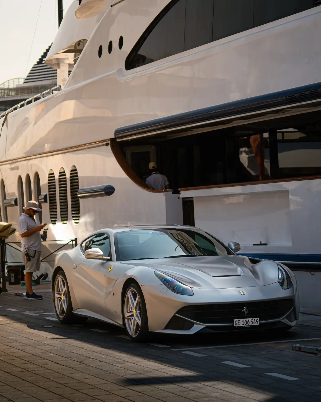 Silberner Ferrari neben einer Yacht im Hafen