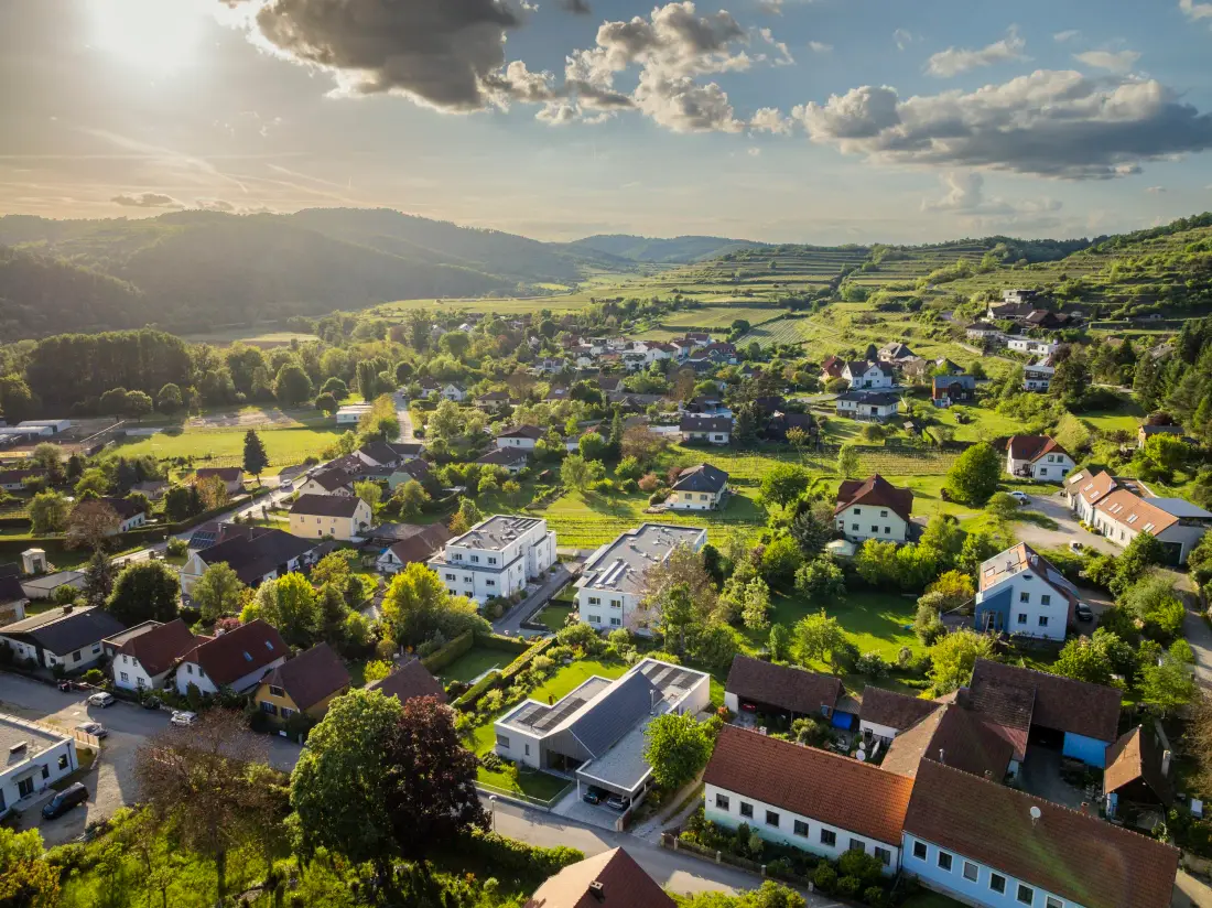 Luftaufnahme einer Ortschaft zwischen Weinbergen und Hügeln
