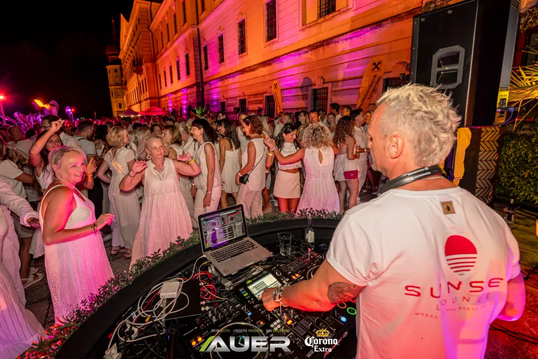 Guests dressed in white dancing in front of the DJ booth