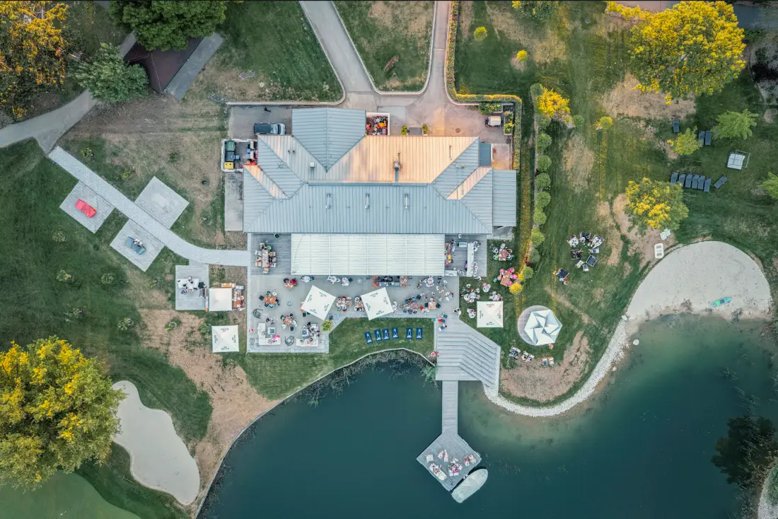 Senkrechte Luftaufnahme eines Lokals am See mit Steg und Strand