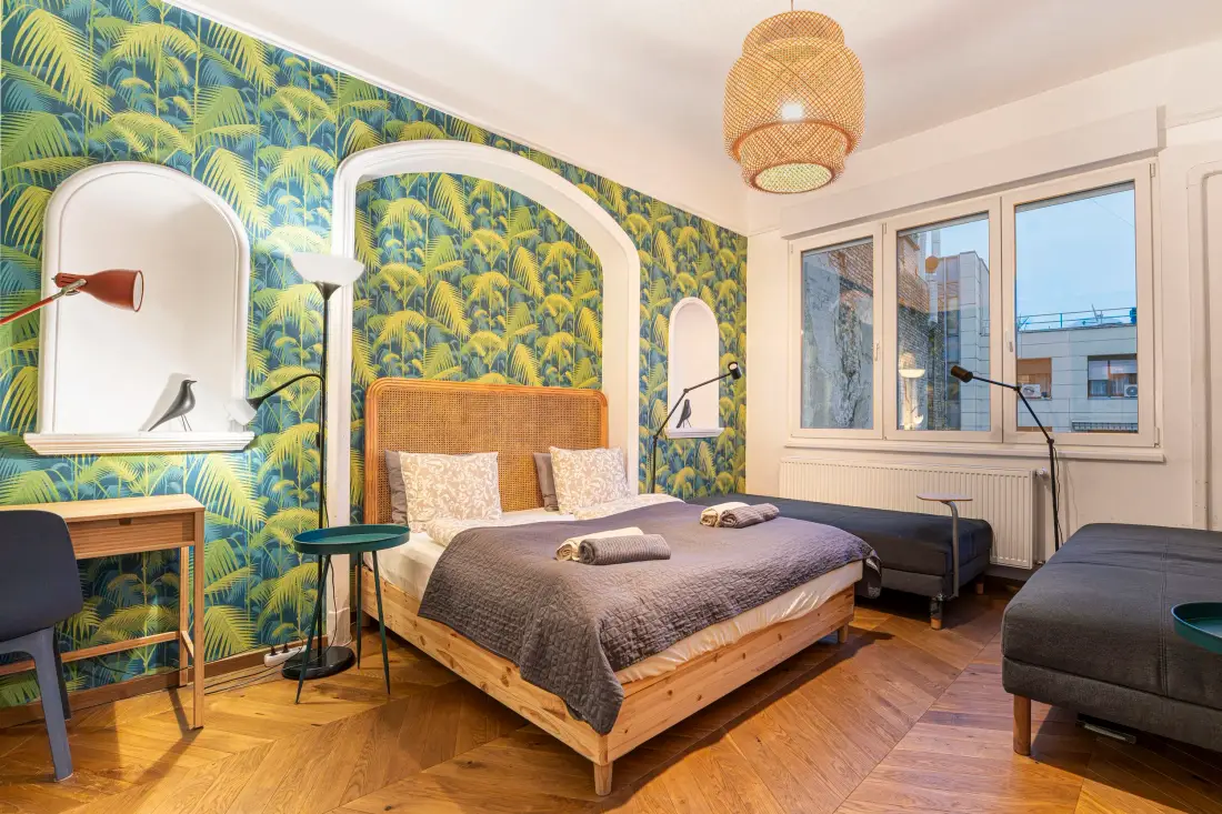Schlafzimmer mit Palmentapete, Doppelbett und Rattanlampe