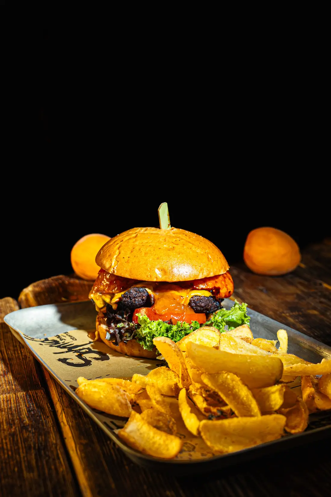 Burger mit Pommes auf einem Tablett vor dunklem Hintergrund