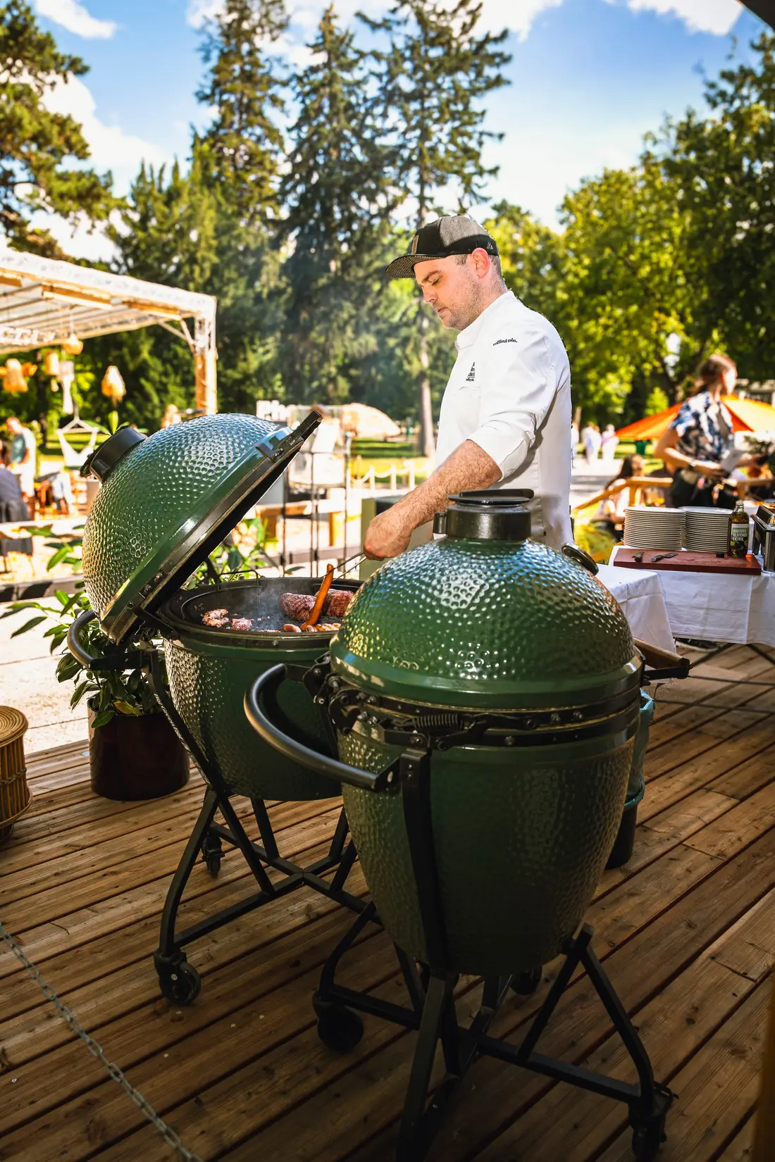 Koch an zwei grünen Keramikgrills auf einer Holzterrasse