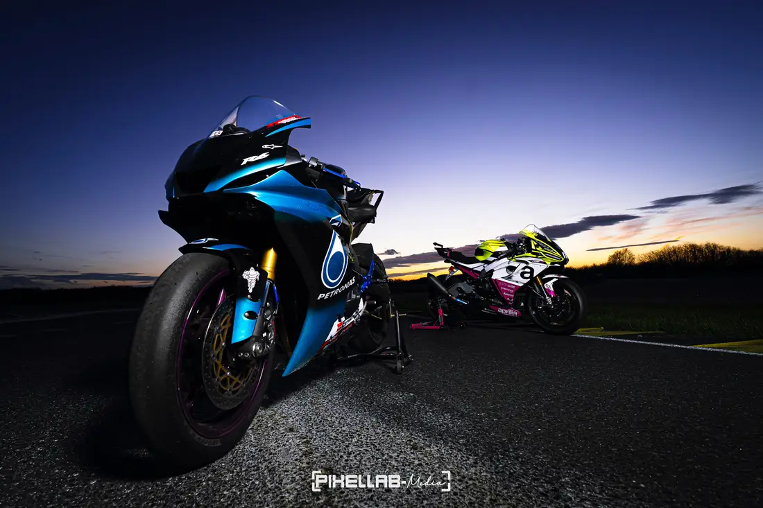 Blaues Rennmotorrad aus der Froschperspektive in der Abenddämmerung, dahinter ein zweites Motorrad