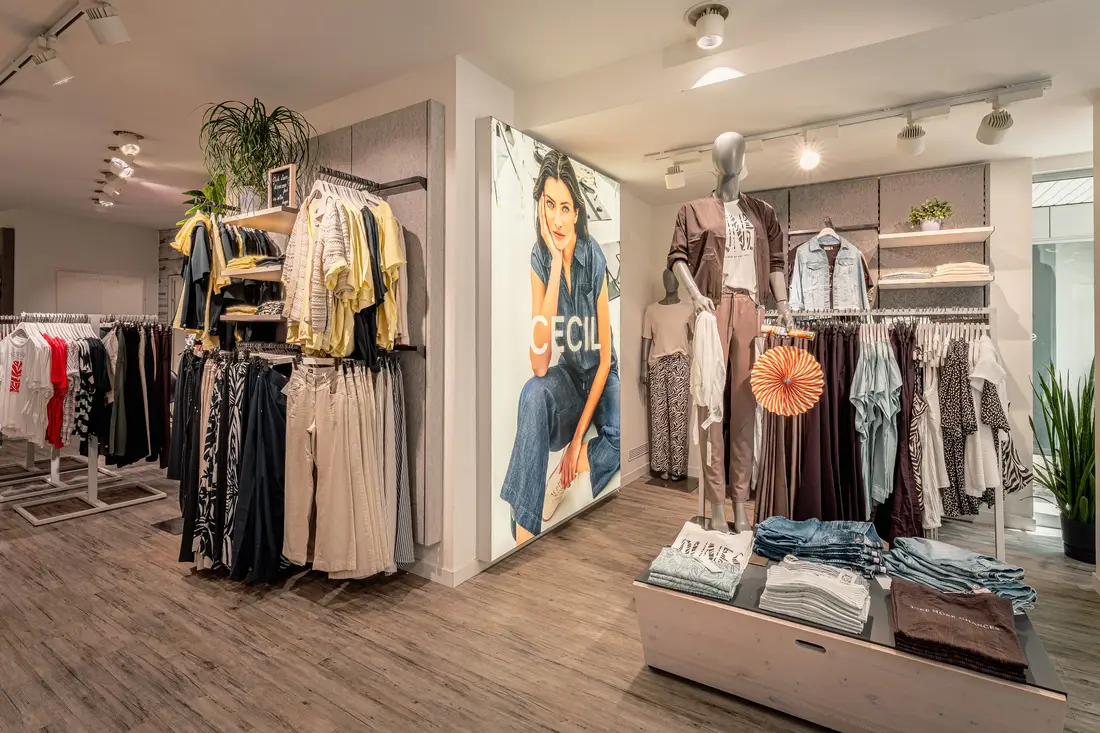 Modegeschäft in Krems mit Kleiderständern, Schaufensterpuppen und großem Werbeplakat