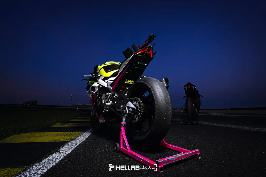 Rennmotorrad auf einem pinken Montageständer auf der Rennstrecke in der Dämmerung