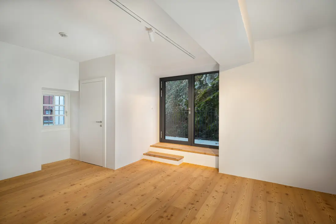 Leerer renovierter Raum mit Holzboden und dunkler Glastür im Museum Lilienfeld