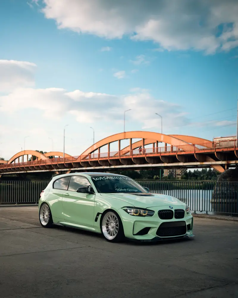 Mint-green BMW in front of a red arch bridge