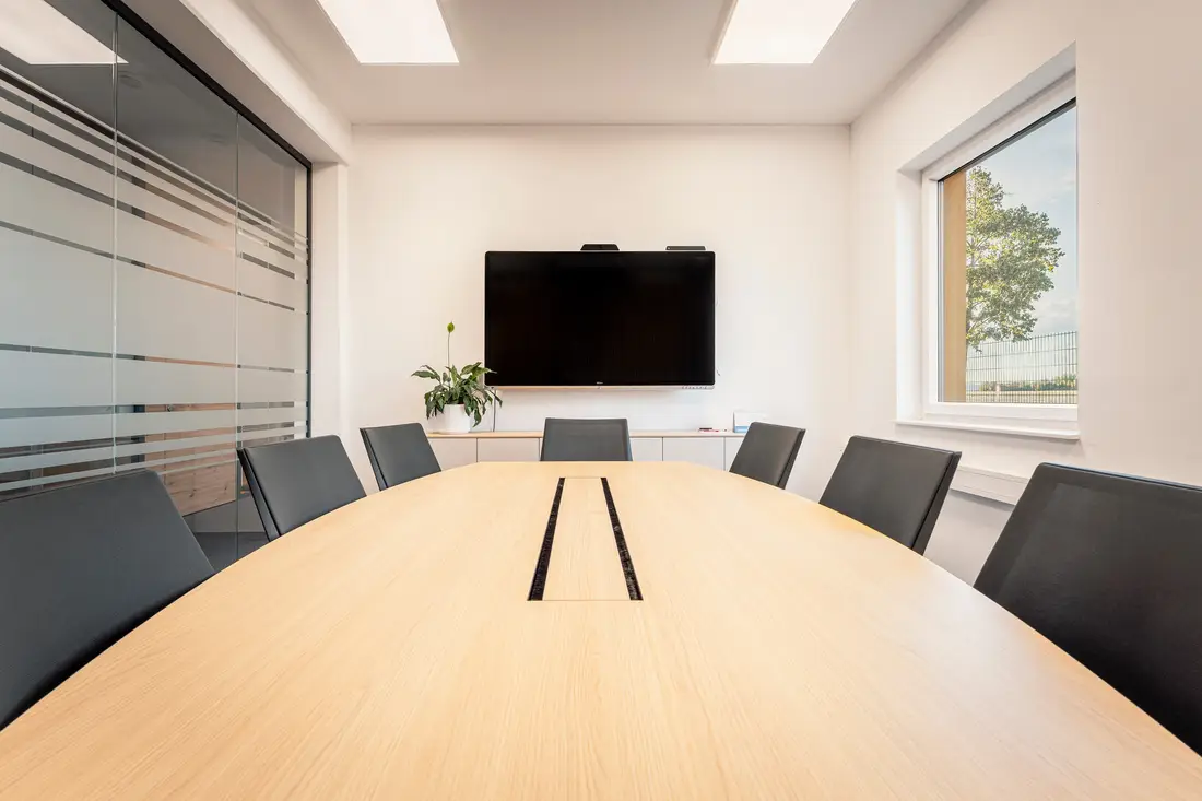 Besprechungsraum im Wagram@Work mit langem Holztisch, Bildschirm und Glaswand