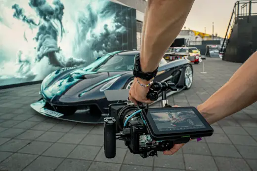 A camera on a gimbal filming a sports car