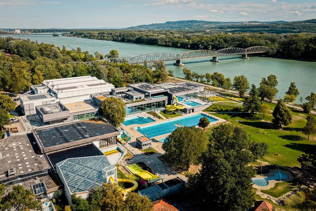 Aerial view of Bad Mirador in Krems an der Donau with pools, a yellow slide and a bridge in the background