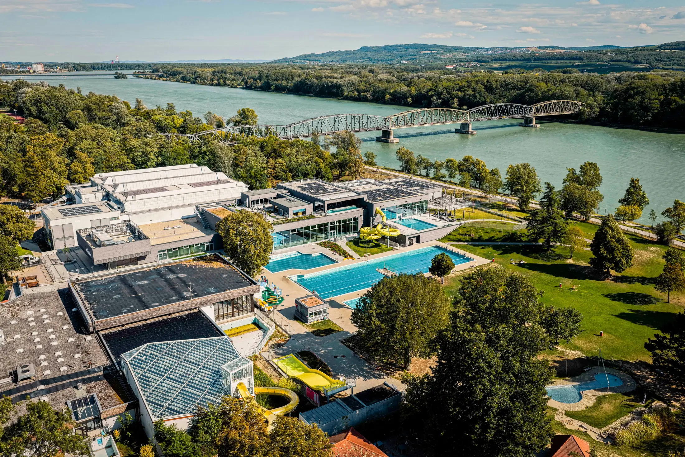 Aerial view of Bad Mirador in Krems an der Donau with pools, a yellow slide and a bridge in the background